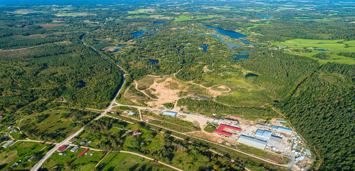 Aerial view of a rural landscape featuring dense forests scattered lakes a small industrial site with buildings and a road network in Latvia. Aerial view of a rural landscape featuring dense forests scattered lakes a small industrial site with buildings and a road network in Latvia.