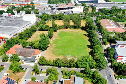 Aerial view of SpVgg Jahn Forchheim Jugendabteilung sports field surrounded by dense green trees and industrial buildings in Forchheim Bayern Germany. Aerial view of SpVgg Jahn Forchheim Jugendabteilung sports field surrounded by dense green trees and industrial buildings in Forchheim Bayern Germany.