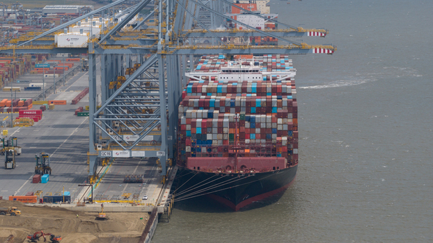 Corringham United Kingdom 10 July 2026 Aerial view of a large container ship docked at London Gateway Port with massive cranes and stacks of colorful shipping containers.