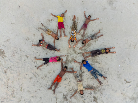 Alakjhari Bangladesh 26 July 2026 Aerial view of children lying in a circular star pattern on the sandy ground at Jharbari ghat.