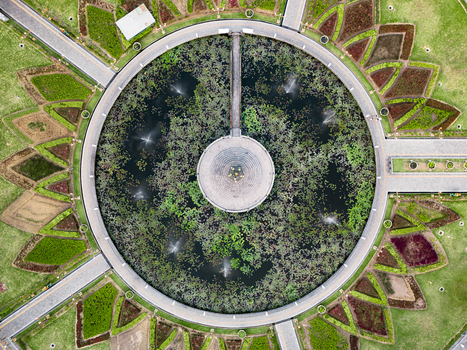 Aerial view of the circular lotus pond and fountain at Alun Alun Tugu Malang surrounded by symmetrical landscaped gardens and pathways in Malang East Java Indonesia.