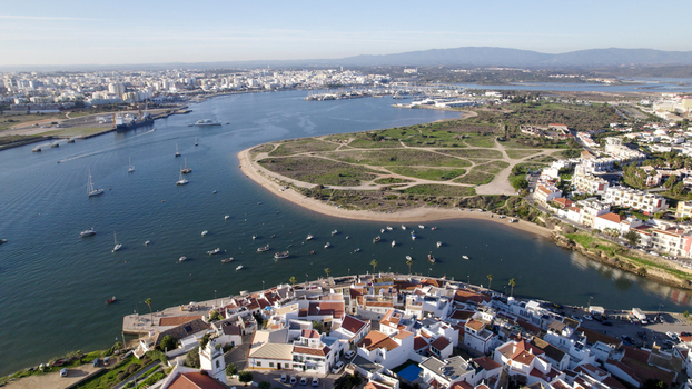Aerial view of the historic village featuring white washed buildings narrow streets and a scenic waterfront with small boats in the Arade River estuary Ferragudo Faro District Portugal.