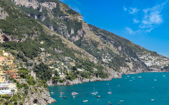 Aerial view of the colorful cliffside village of Positano with its historic buildings steep mountains and boats floating on the turquoise Tyrrhenian Sea in Positano Campania Italy. Aerial view of the colorful cliffside village of Positano with its historic buildings steep mountains and boats floating on the turquoise Tyrrhenian Sea in Positano Campania Italy.