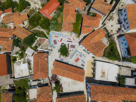 Aerial view of a traditional village square with orange terracotta rooftops stone paved streets and a central tree in Dhermi Vlore County Albania. Aerial view of a traditional village square with orange terracotta rooftops stone paved streets and a central tree in Dhermi Vlore County Albania.