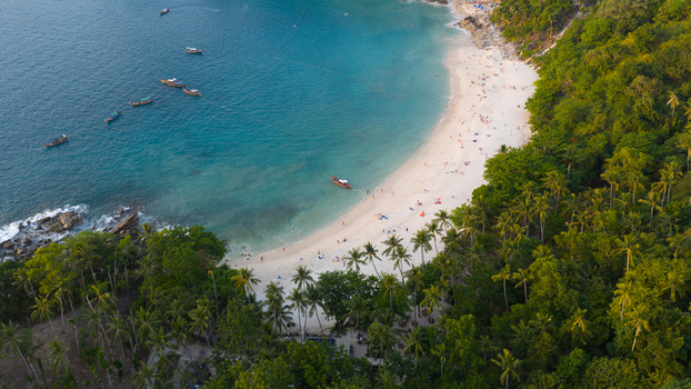 Aerial view of Freedom Beach with white sand turquoise water and longtail boats anchored near the shore in Tambon Patong Chang Wat Phuket Thailand.