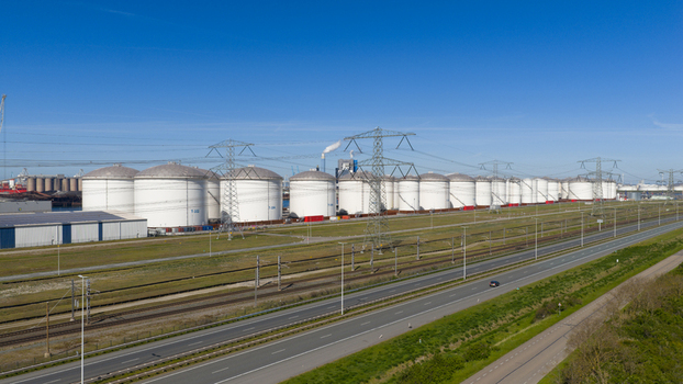 Aerial view of the Port of Rotterdam featuring large industrial storage tanks power lines and a highway under a clear blue sky in Rotterdam Zuid Holland Netherlands. Aerial view of the Port of Rotterdam featuring large industrial storage tanks power lines and a highway under a clear blue sky in Rotterdam Zuid Holland Netherlands.