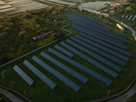 Aerial view of rows of photovoltaic solar panels installed on a green field surrounded by trees and rural buildings in Augusta Sicily Italy. Aerial view of rows of photovoltaic solar panels installed on a green field surrounded by trees and rural buildings in Augusta Sicily Italy.