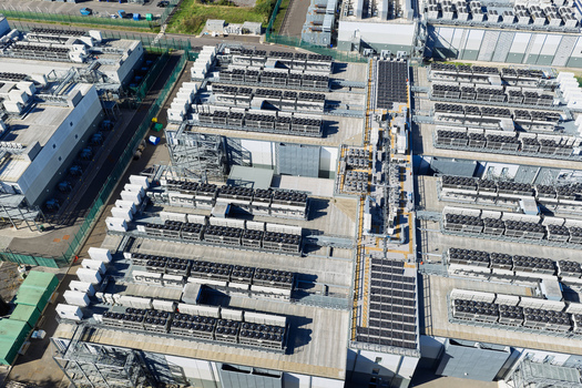 Aerial view of a large data center facility featuring rows of cooling units and industrial equipment on the roof in the United Kingdom.