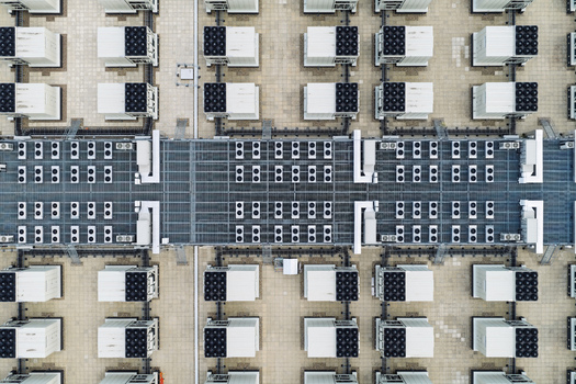 Aerial view of a data center roof featuring rows of industrial HVAC cooling units and ventilation systems arranged in a grid pattern in the United Kingdom.