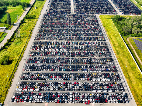Aerial view of thousands of new cars parked in organized rows at a massive logistics hub surrounded by green fields and solar panels in Rivalta di Torino Piedmont Italy. Aerial view of thousands of new cars parked in organized rows at a massive logistics hub surrounded by green fields and solar panels in Rivalta di Torino Piedmont Italy.