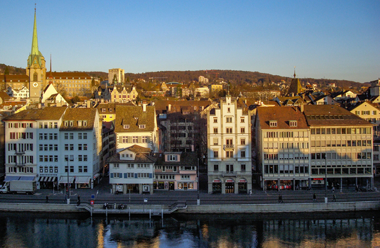 View of the historic Limmat riverfront in Zurich featuring traditional architecture the Fraumunster church spire and reflections on the water in Zurich Zurich Switzerland.