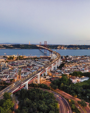 Aerial view of April 25th bridge with Christ the King statue Cristo Rei in background at sunset view of Lisbon skyline at night Alc&acirc;ntara Lisbon Portugal.