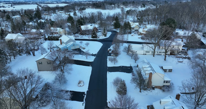 Aerial view of a suburban neighborhood covered in fresh snow featuring cleared roads residential houses with snow covered roofs and trees Lititz Pennsylvania United States.