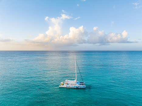 Aerial view of a catamaran sailing on the turquoise waters of Grace Bay under a bright sky with fluffy clouds Grace Bay Caicos Islands Turks and Caicos Islands. Aerial view of a catamaran sailing on the turquoise waters of Grace Bay under a bright sky with fluffy clouds Grace Bay Caicos Islands Turks and Caicos Islands.