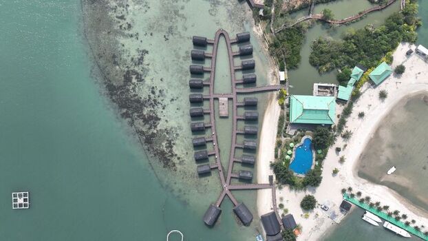 Aerial view of Pulau Lima Resort featuring overwater bungalows in a fish like pattern with wooden walkways a swimming pool and sandy beach in Kasemen Banten Indonesia. Aerial view of Pulau Lima Resort featuring overwater bungalows in a fish like pattern with wooden walkways a swimming pool and sandy beach in Kasemen Banten Indonesia.