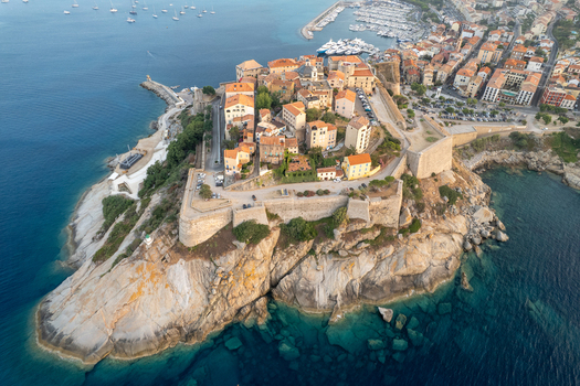Aerial view of the historic Citadelle de Calvi perched on a rocky promontory overlooking the Mediterranean Sea with stone fortifications and terracotta rooftops in Calvi Corse France.