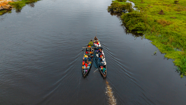 Aerial view of two wooden boats filled with people and goods navigating the dark waters of the river in Itu Akwa Ibom Nigeria. Aerial view of two wooden boats filled with people and goods navigating the dark waters of the river in Itu Akwa Ibom Nigeria.