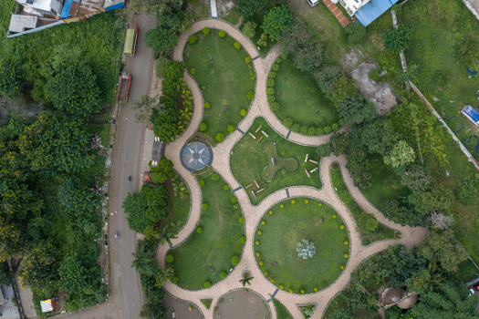 Aerial view of a public park in Karad featuring geometric walking paths lush green lawns manicured shrubs and a central compass style design Karad Maharashtra India.