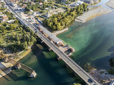 Aerial view of Ura e Bahcallekut bridge under construction with heavy machinery and a crane over the Drin river in Bahcallek Shkoder County Albania. Aerial view of Ura e Bahcallekut bridge under construction with heavy machinery and a crane over the Drin river in Bahcallek Shkoder County Albania.