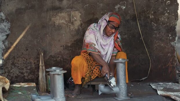 View of a woman using an angle grinder in a workshop Bangladesh.