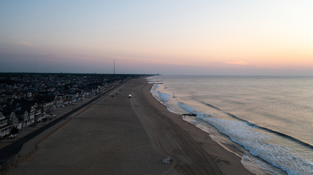 Aerial view of Manasquan Beach at sunrise with calm waves sandy shoreline and coastal houses along the boardwalk in Manasquan New Jersey United States. Aerial view of Manasquan Beach at sunrise with calm waves sandy shoreline and coastal houses along the boardwalk in Manasquan New Jersey United States.