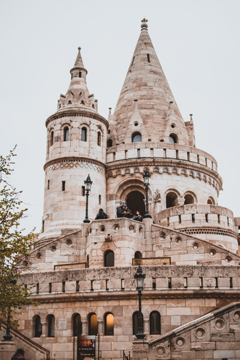 View of the Fisherman s Bastion a magnificent neo Romanesque terrace stands tall against a soft sky its intricate stone details catching the light Budapest Hungary. View of the Fisherman s Bastion a magnificent neo Romanesque terrace stands tall against a soft sky its intricate stone details catching the light Budapest Hungary.