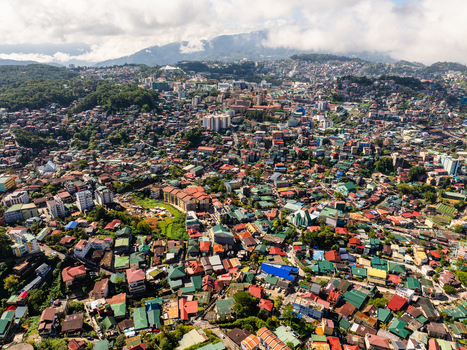 Aerial view of the densely populated urban landscape with colorful rooftops nestled among rolling hills and misty mountains Baguio Cordillera Administrative Region Philippines.