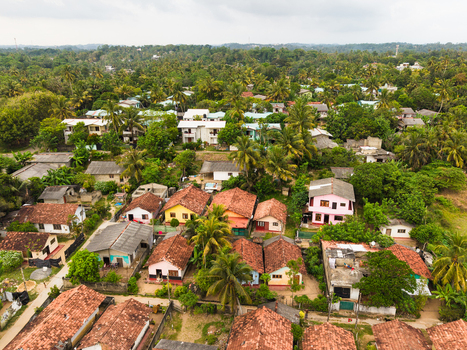 Aerial view of colorful houses with tiled rooftops nestled among lush tropical greenery and palm trees in Galle Southern Province Sri Lanka. Aerial view of colorful houses with tiled rooftops nestled among lush tropical greenery and palm trees in Galle Southern Province Sri Lanka.