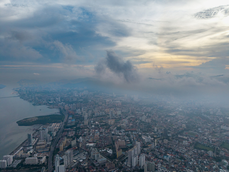 Aerial view of George Town with dense urban buildings coastal roads and scattered clouds over the sea in George Town Penang Malaysia. Aerial view of George Town with dense urban buildings coastal roads and scattered clouds over the sea in George Town Penang Malaysia.