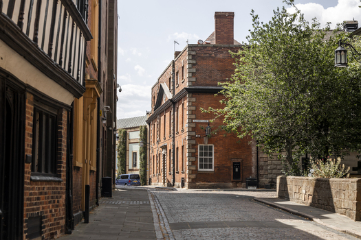 View of a historic cobblestone street with traditional red brick buildings and timber framed architecture in Coventry England United Kingdom.