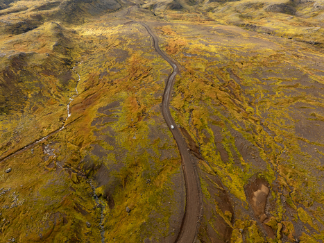 Aerial view of a lone vehicle winding through a rugged landscape painted in autumnal hues Snæfellsnes Eyja og Miklaholtshreppur Iceland. Aerial view of a lone vehicle winding through a rugged landscape painted in autumnal hues Snæfellsnes Eyja og Miklaholtshreppur Iceland.