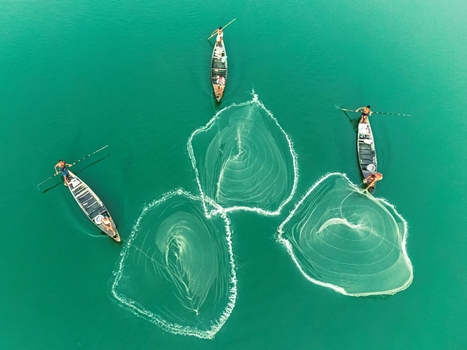 Khansama Upazila Bangladesh 11 June 2026 Aerial view of fishermen in small wooden boats casting circular nets into the turquoise water of a river.