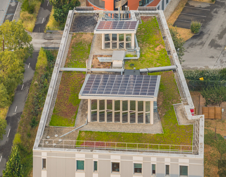 Aerial view of a modern building featuring a sustainable green roof with integrated photovoltaic solar panels and technical rooftop installations in Alixan Auvergne Rhone Alpes France.
