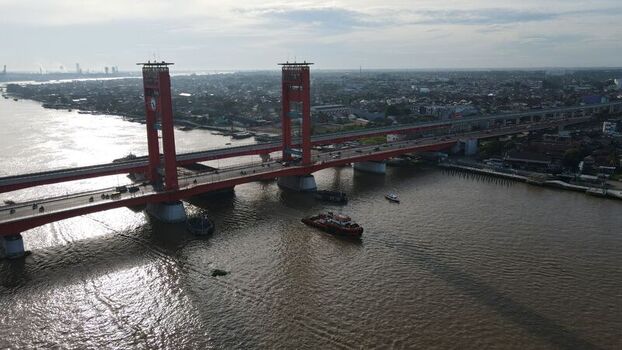 Aerial view of the red Ampera Bridge spanning the Musi River in Palembang with urban surroundings and boats in Kecamatan Seberang Ulu I Sumatera Selatan Indonesia. Aerial view of the red Ampera Bridge spanning the Musi River in Palembang with urban surroundings and boats in Kecamatan Seberang Ulu I Sumatera Selatan Indonesia.
