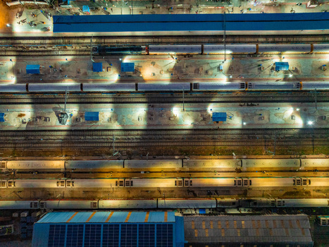 Aerial view of a train station at night with illuminated platforms and parked trains along the tracks in Udaipur Rajasthan India. Aerial view of a train station at night with illuminated platforms and parked trains along the tracks in Udaipur Rajasthan India.