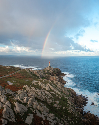 Aerial view of Faro de Punta Nariga lighthouse on a rugged rocky coastline with a vibrant rainbow over the Atlantic Ocean Malpica A Coruna Spain. Aerial view of Faro de Punta Nariga lighthouse on a rugged rocky coastline with a vibrant rainbow over the Atlantic Ocean Malpica A Coruna Spain.