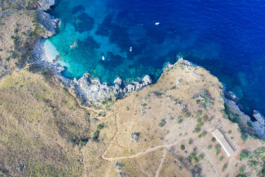 Aerial view of Riserva Naturale Orientata dello Zingaro with turquoise waters rocky cliffs and small boats in San Vito Lo Capo Sicilia Italy. Aerial view of Riserva Naturale Orientata dello Zingaro with turquoise waters rocky cliffs and small boats in San Vito Lo Capo Sicilia Italy.