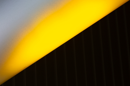 View of a stark contrast where bright yellow light dramatically intersects with a deep black textured surface and a soft grey area La Defense Flevoland Netherlands. View of a stark contrast where bright yellow light dramatically intersects with a deep black textured surface and a soft grey area La Defense Flevoland Netherlands.