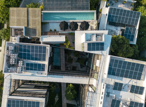 Aerial view of a modern building in Merida featuring a swimming pool black umbrellas and extensive rooftop solar panel arrays in Merida Yucatan Mexico. Aerial view of a modern building in Merida featuring a swimming pool black umbrellas and extensive rooftop solar panel arrays in Merida Yucatan Mexico.