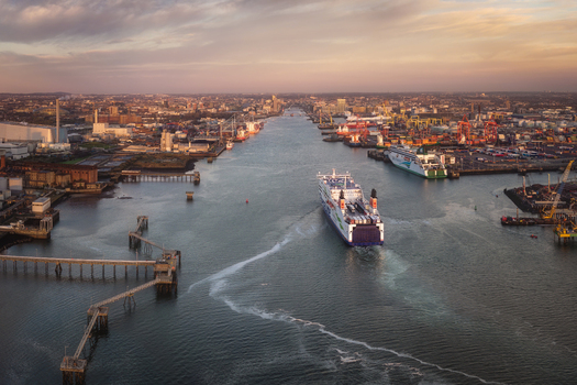 Aerial view of Dublin Port with a large ferry navigating the channel towards the city skyline under a golden sunset Dublin County Dublin Ireland. Aerial view of Dublin Port with a large ferry navigating the channel towards the city skyline under a golden sunset Dublin County Dublin Ireland.