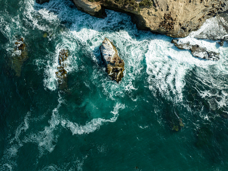 Aerial view of La Jolla Cove with turquoise ocean waves crashing against rugged rocks and sea lions resting on the shore in San Diego California United States. Aerial view of La Jolla Cove with turquoise ocean waves crashing against rugged rocks and sea lions resting on the shore in San Diego California United States.