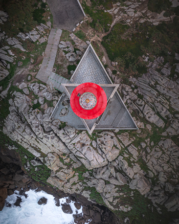 Aerial view of Faro de Punta Nariga lighthouse featuring its red lantern and triangular base on rocky cliffs by the ocean in Malpica A Coruna Spain. Aerial view of Faro de Punta Nariga lighthouse featuring its red lantern and triangular base on rocky cliffs by the ocean in Malpica A Coruna Spain.