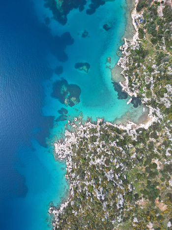 Aerial view of the rugged coastline and turquoise waters of the Mediterranean Sea near the historic ruins of Simena in Demre Antalya Turkiye. Aerial view of the rugged coastline and turquoise waters of the Mediterranean Sea near the historic ruins of Simena in Demre Antalya Turkiye.