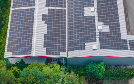 Aerial view of a large industrial warehouse roof covered with solar photovoltaic panels showcasing renewable energy infrastructure in Loriol sur Drome Auvergne Rhone Alpes France.
