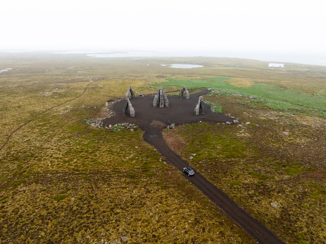 Aerial view of Arctic Henge surrounded by vast tundra and a gravel road with a car in Raufarhofn Nordurthing Iceland.