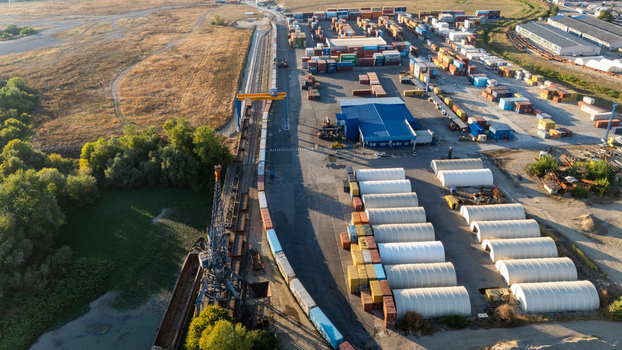 Sremska Mitrovica Serbia 16 September 2026 Aerial view of the industrial port and railway terminal featuring rows of shipping containers white storage warehouses and a gantry crane along the riverbank. Sremska Mitrovica Serbia 16 September 2026 Aerial view of the industrial port and railway terminal featuring rows of shipping containers white storage warehouses and a gantry crane along the riverbank.