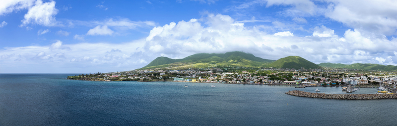 Aerial view of the coastal city with its harbor and lush green volcanic mountains under a cloudy sky in Basseterre Saint George Basseterre Saint Kitts and Nevis.
