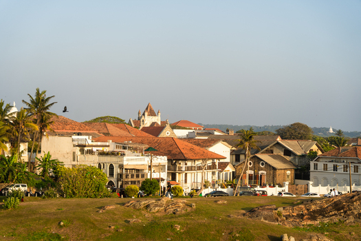 View of historic colonial buildings with red tiled roofs and palm trees under a clear sky from the grassy ramparts of the fort Galle Southern Province Sri Lanka.