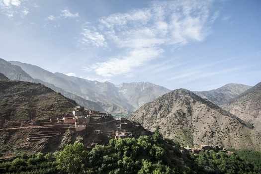 View of the traditional Berber village of Tizi Oussem nestled on a hillside with rugged Atlas Mountains and lush greenery under a blue sky Tizi Oussem Marrakech Safi Morocco. View of the traditional Berber village of Tizi Oussem nestled on a hillside with rugged Atlas Mountains and lush greenery under a blue sky Tizi Oussem Marrakech Safi Morocco.