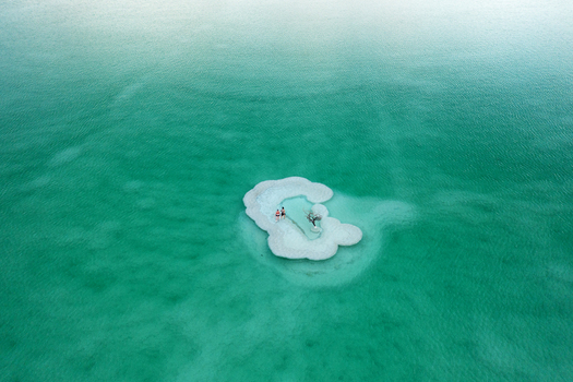 Aerial view of a small island in the Dead Sea its white salt formations contrasting with the turquoise water Ein Bokek South District Israel. Aerial view of a small island in the Dead Sea its white salt formations contrasting with the turquoise water Ein Bokek South District Israel.